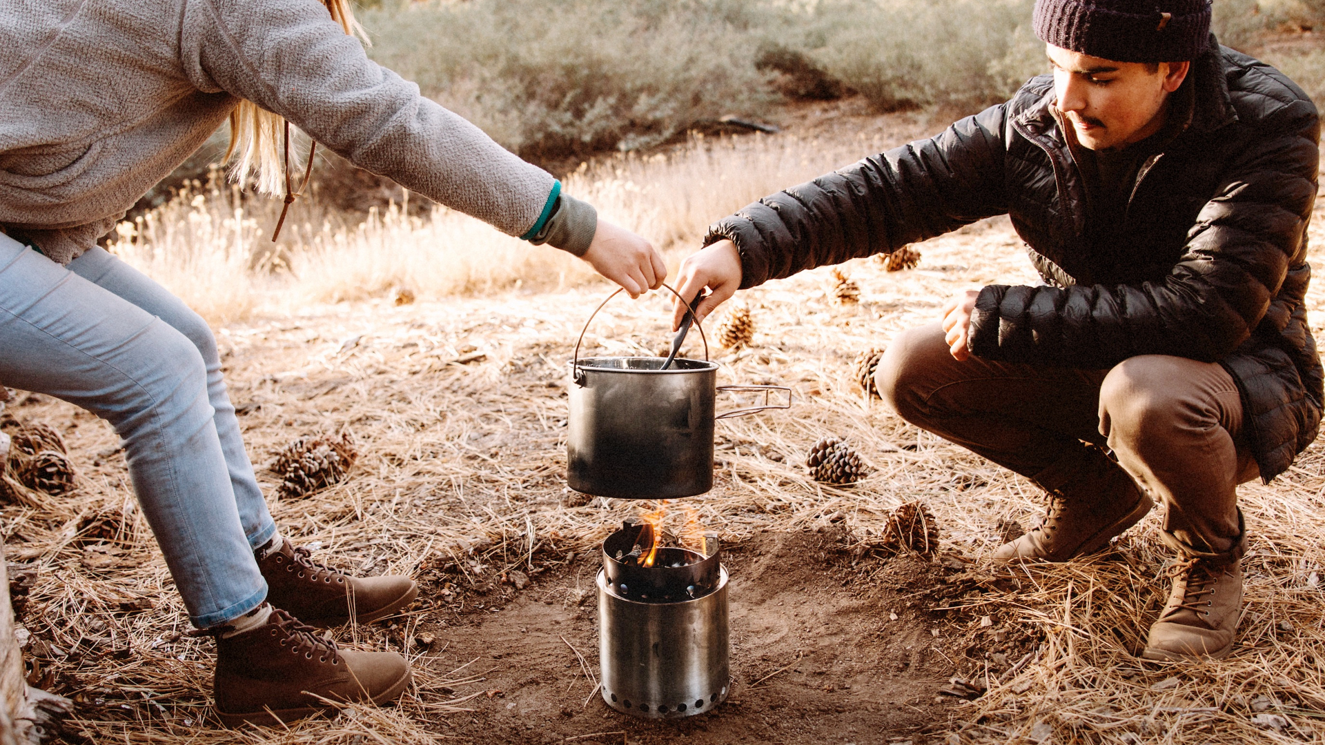 Un hombre y una mujer cocinando con una estufa de camping.
