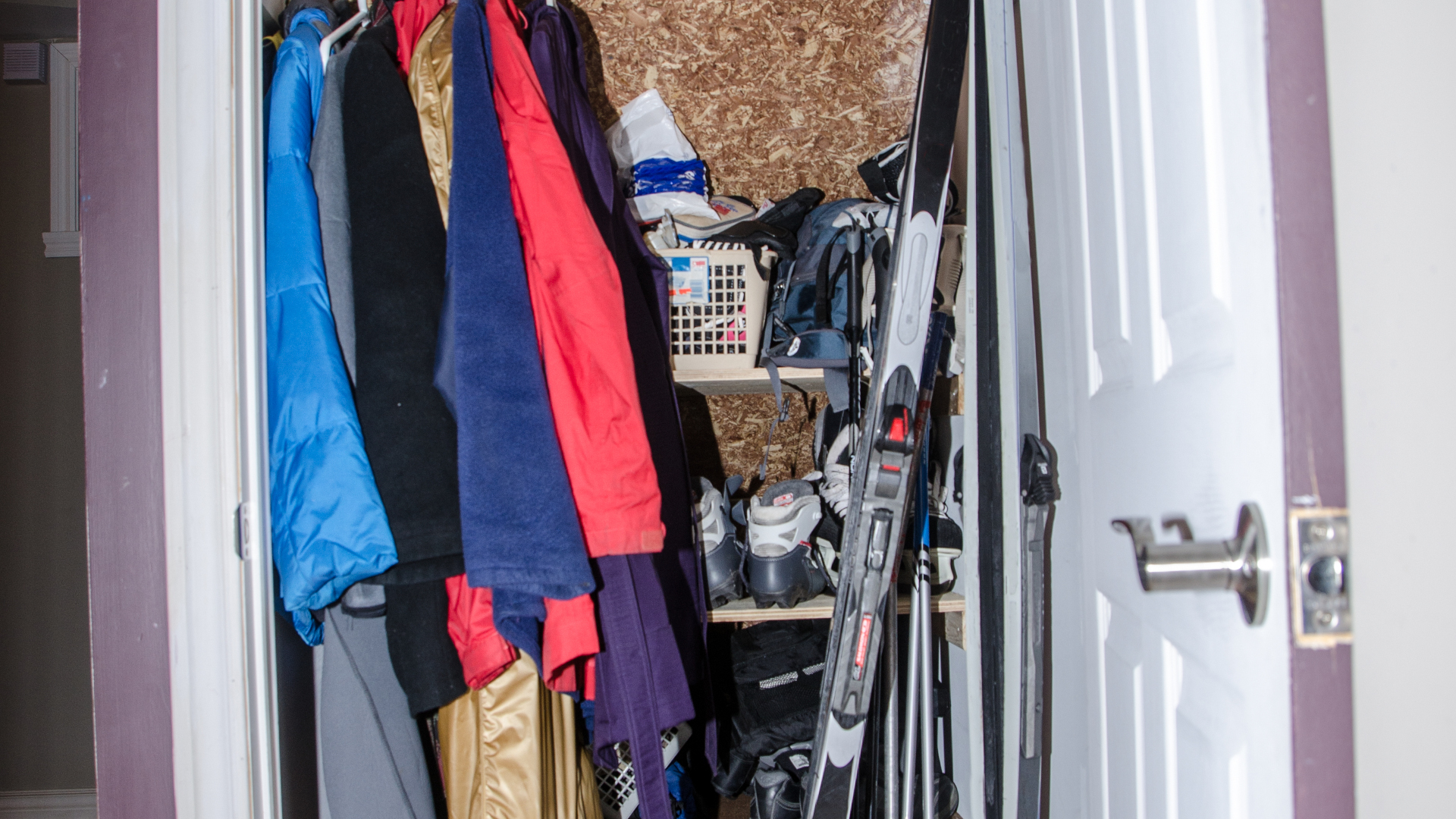 Un armario desordenado con esquís y otros equipos.