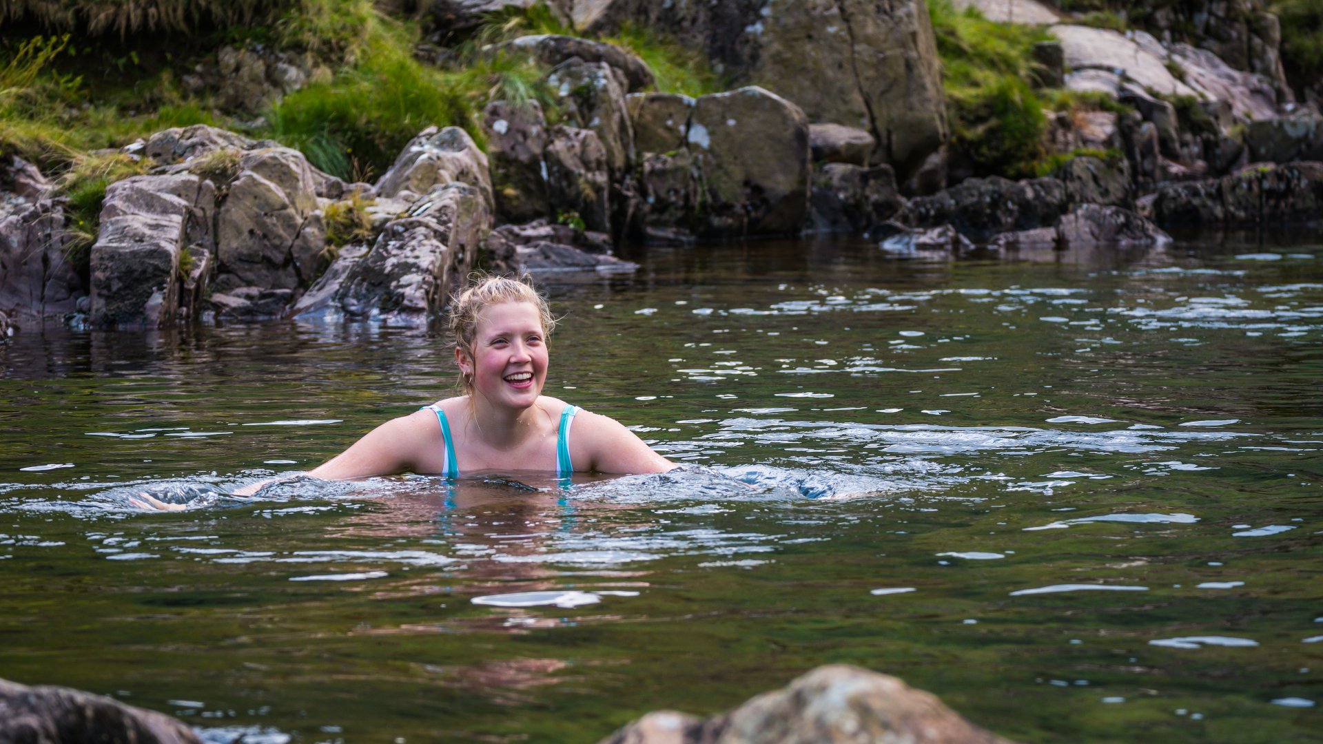 Una mujer salvaje nadando en un claro arroyo de montaña Lake District Cumbria.jpg