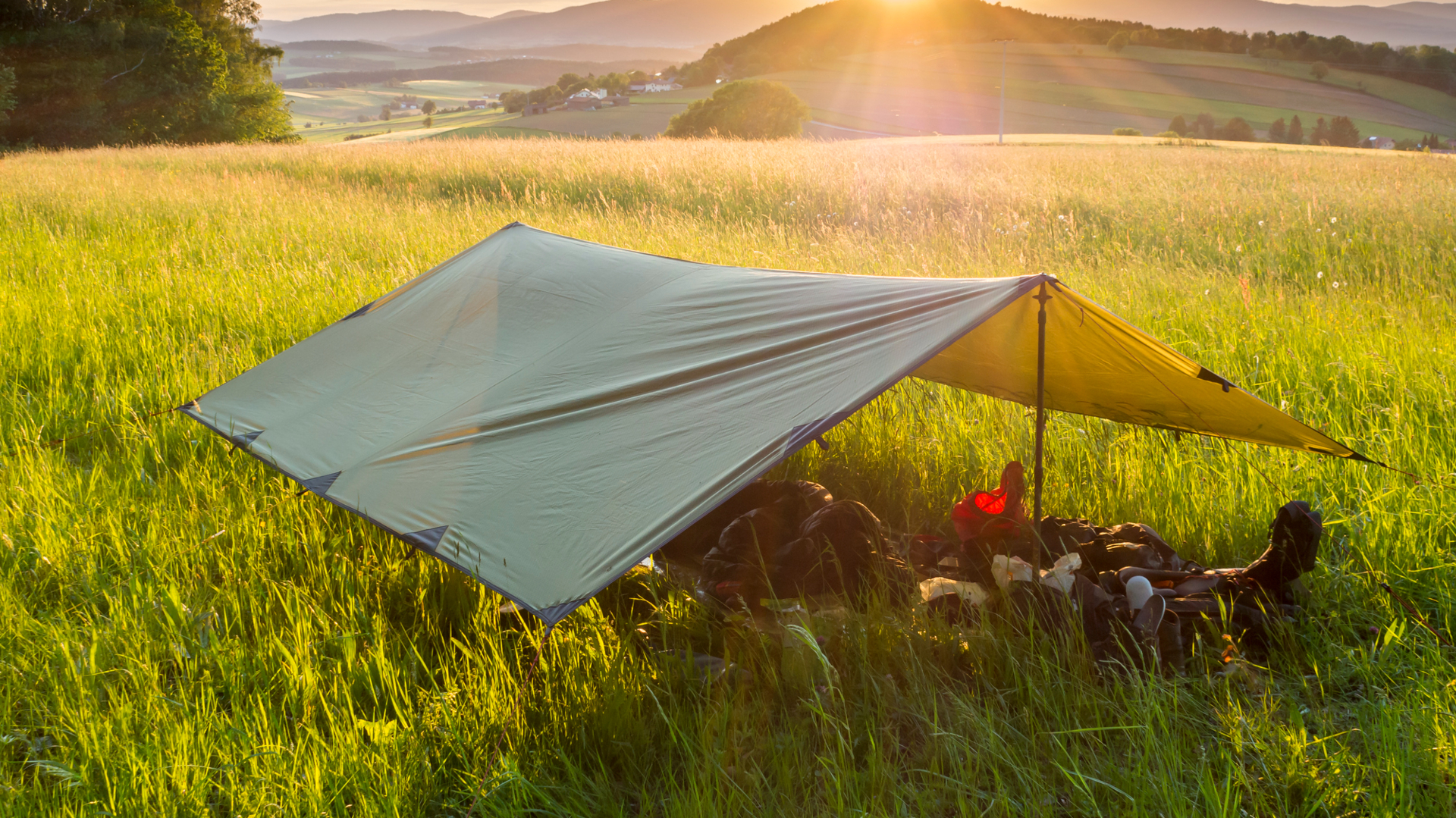 una lona estirada sobre equipo de campamento en un campo