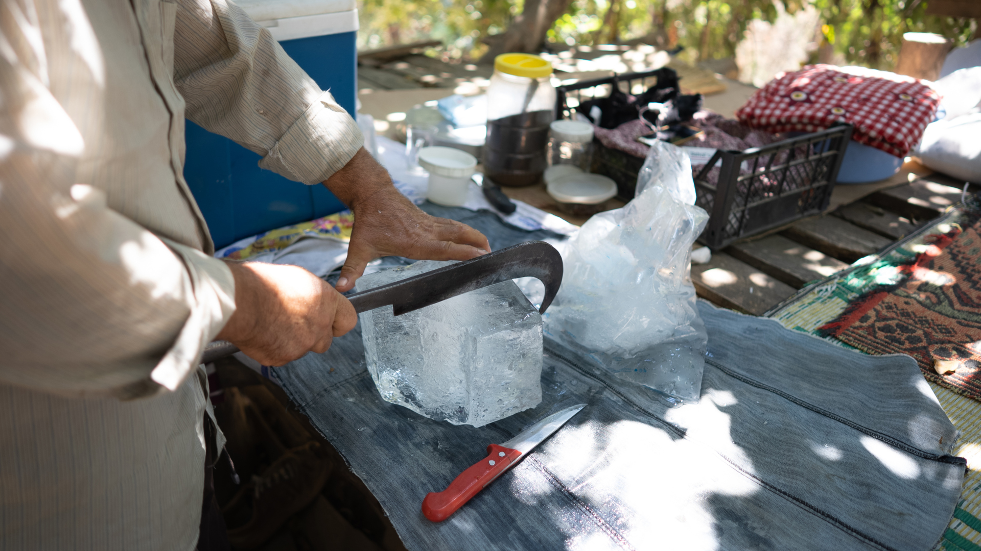 Un hombre cortando hielo de un bloque en un campamento