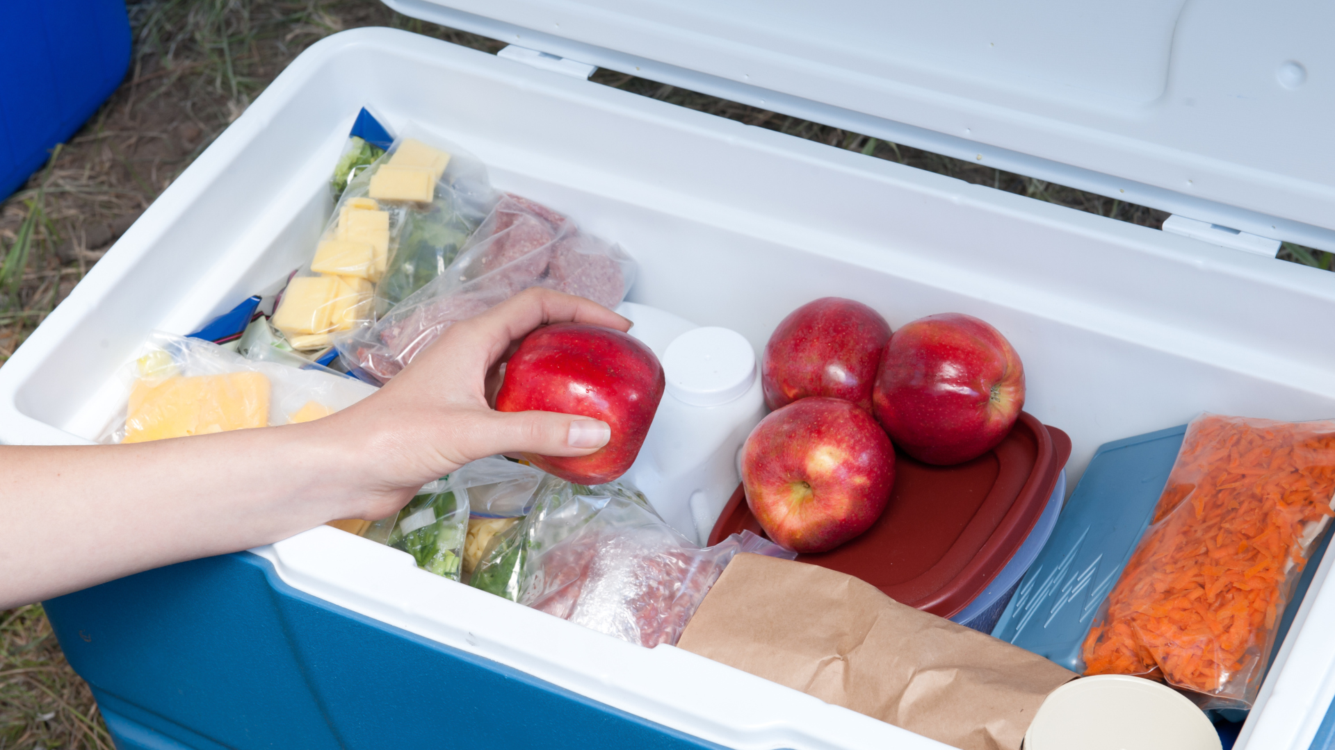 Una mano alcanza una manzana en un refrigerador