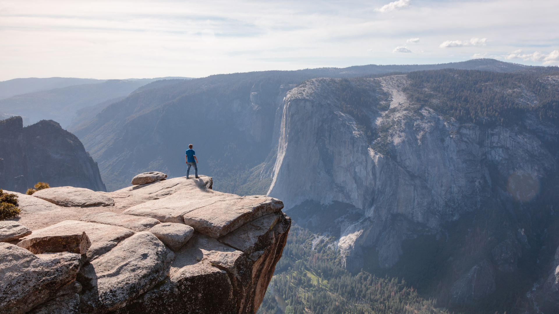 Un hombre de pie en el borde de un acantilado con vistas al valle de Yosemite