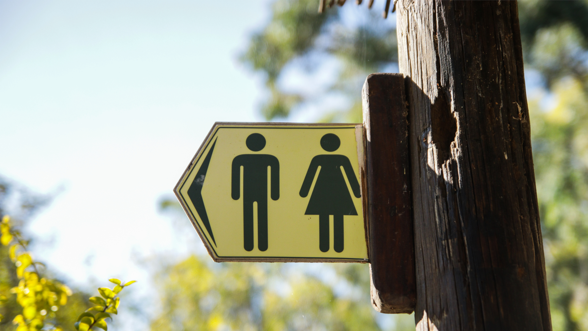Señal de baños públicos para hombres y mujeres con fondo amarillo