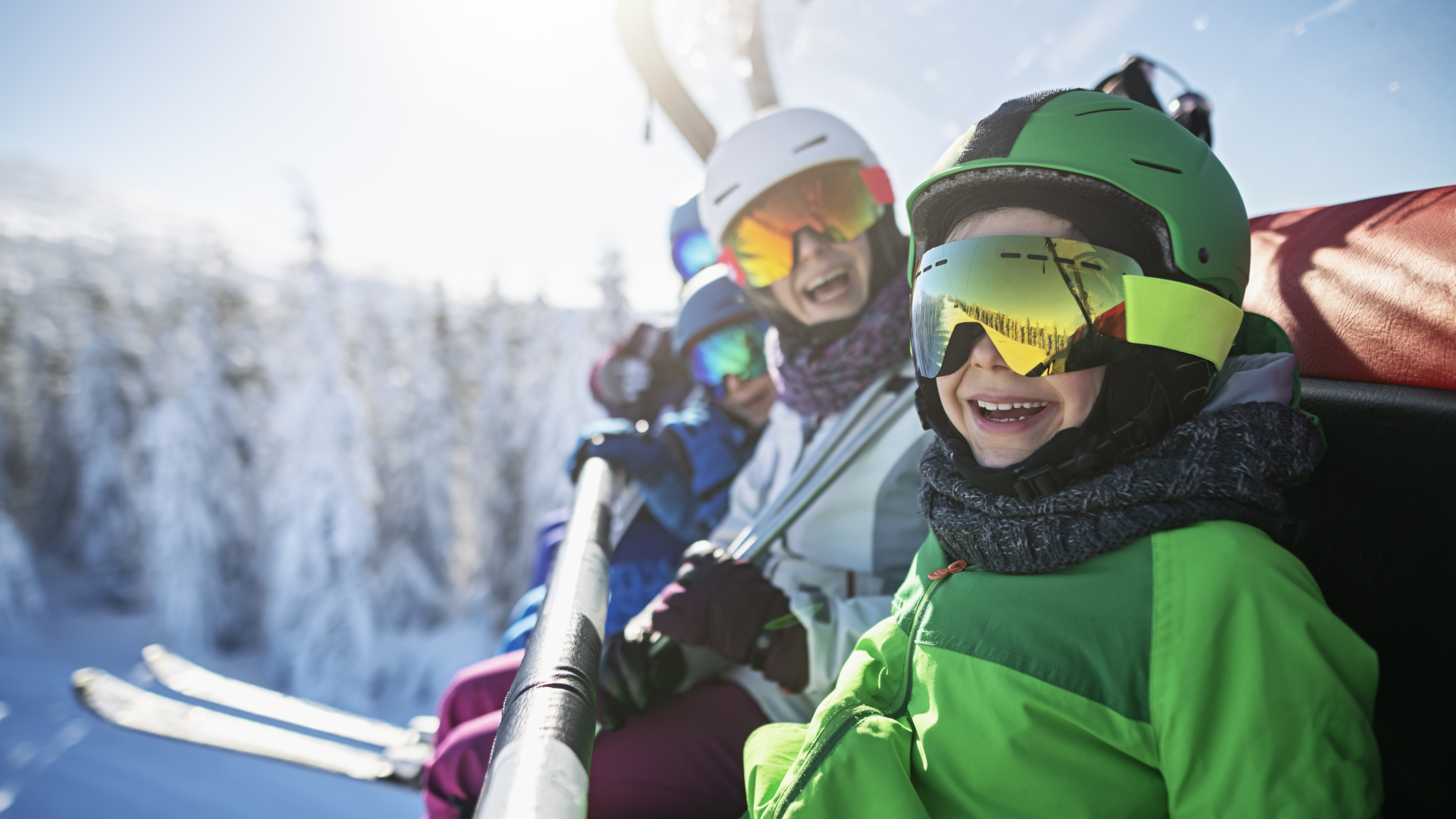 Una familia de esquiadores sonriendo en el telesilla en un día soleado