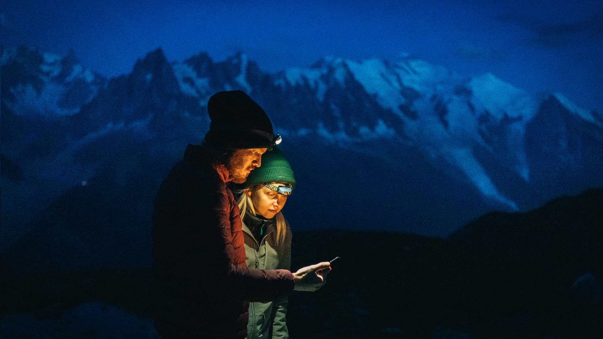 Una pareja examinando un mapa con faros en la noche