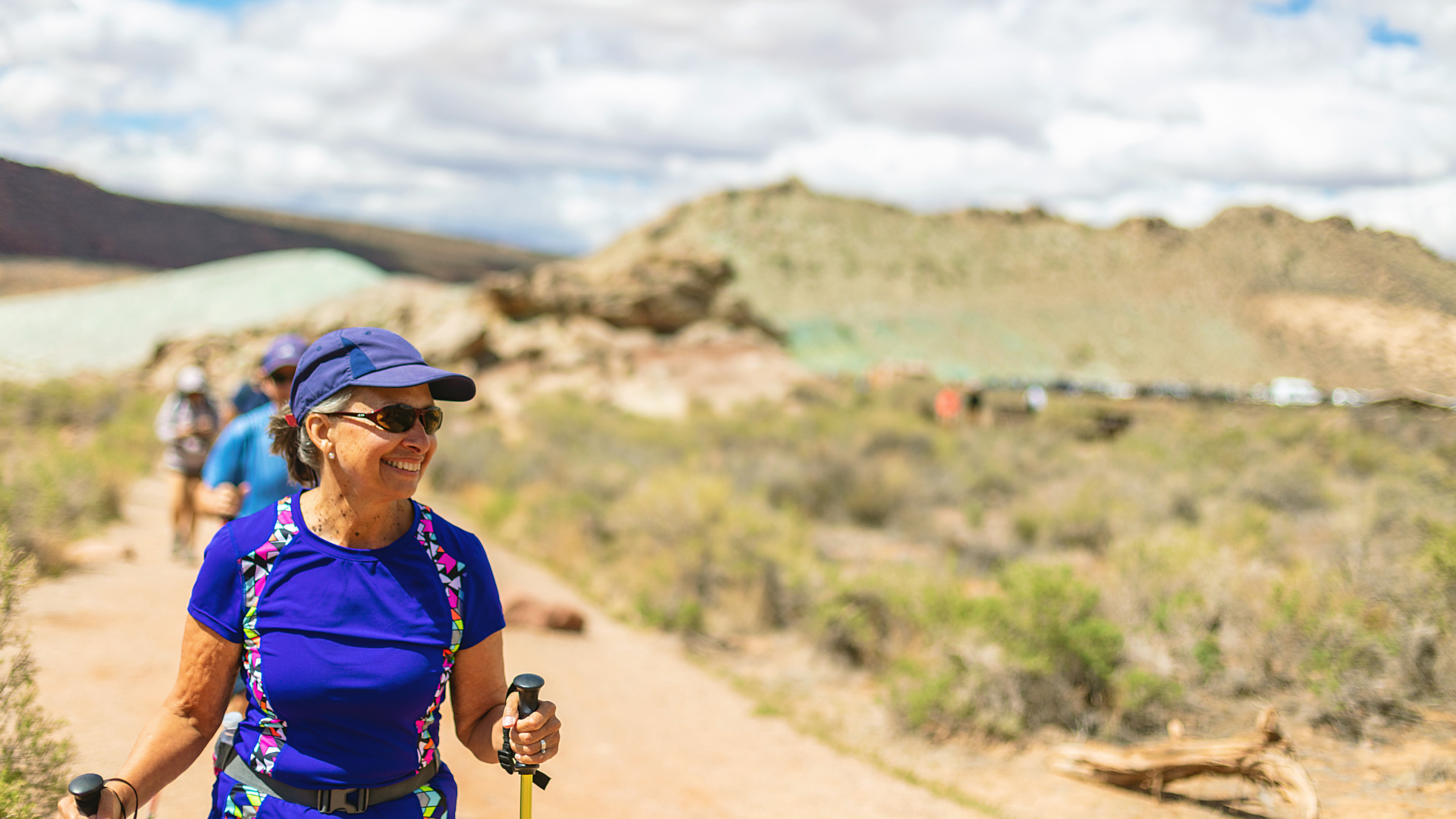 Una mujer camina por el desierto con sombrero y gafas de sol.