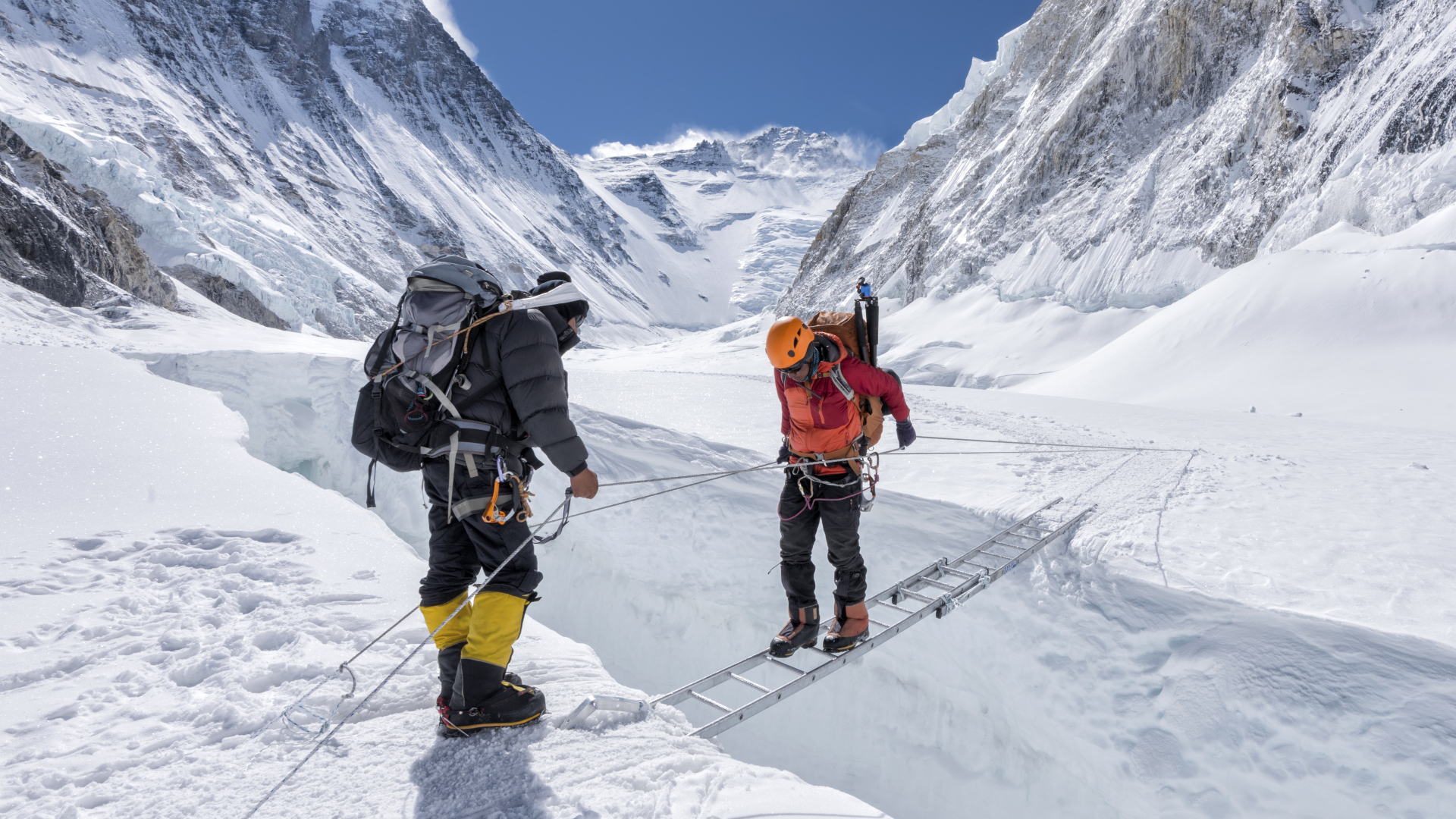 Dos hombres cruzan una grieta en un glaciar usando una escalera