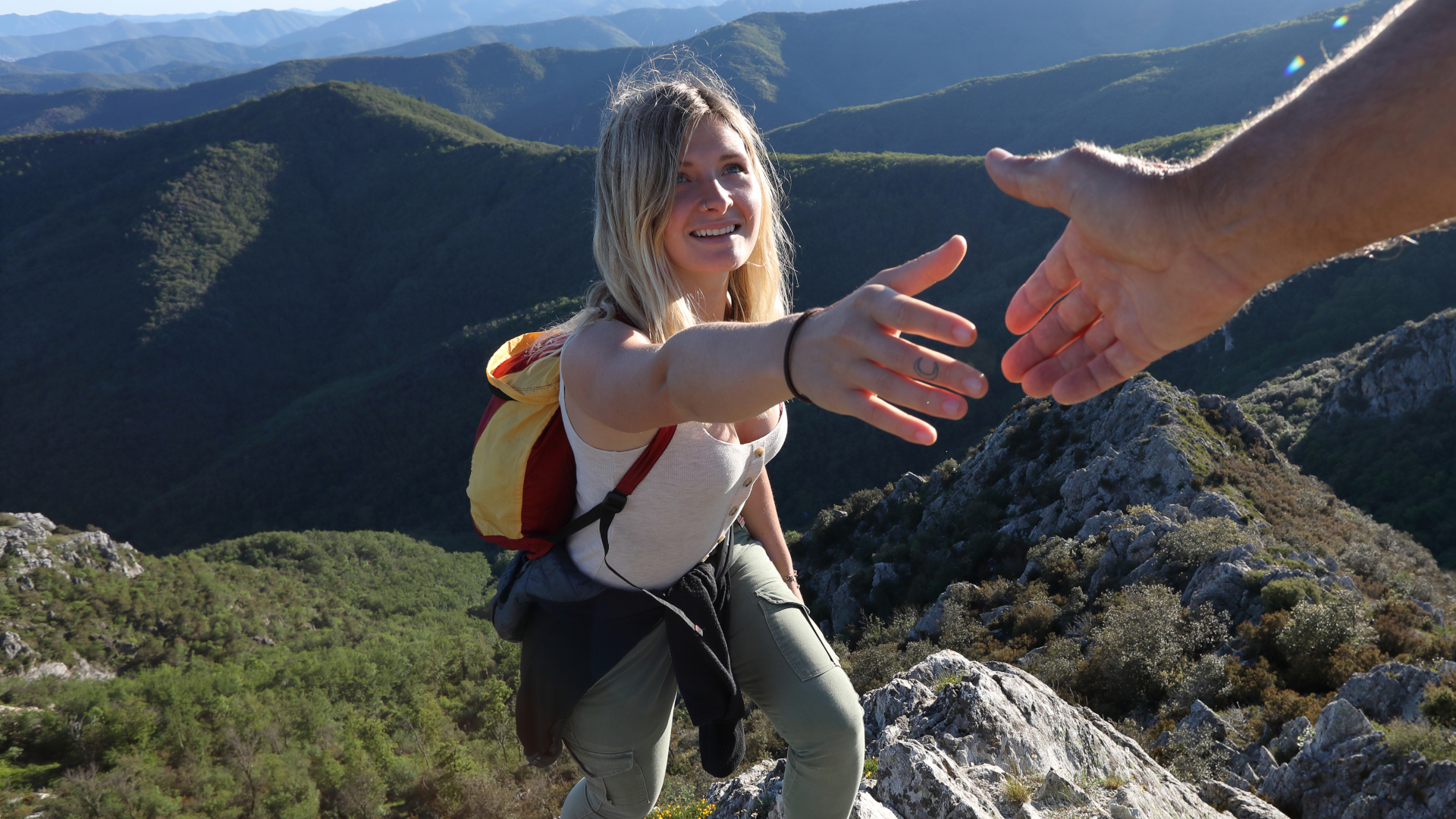 Un excursionista extiende una mano para que un guía lo ayude a subir una montaña.