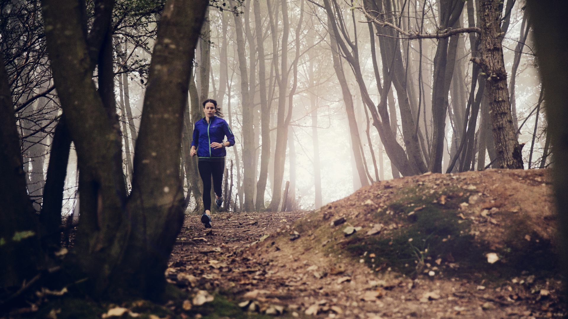 Una mujer corriendo por un sendero en el bosque