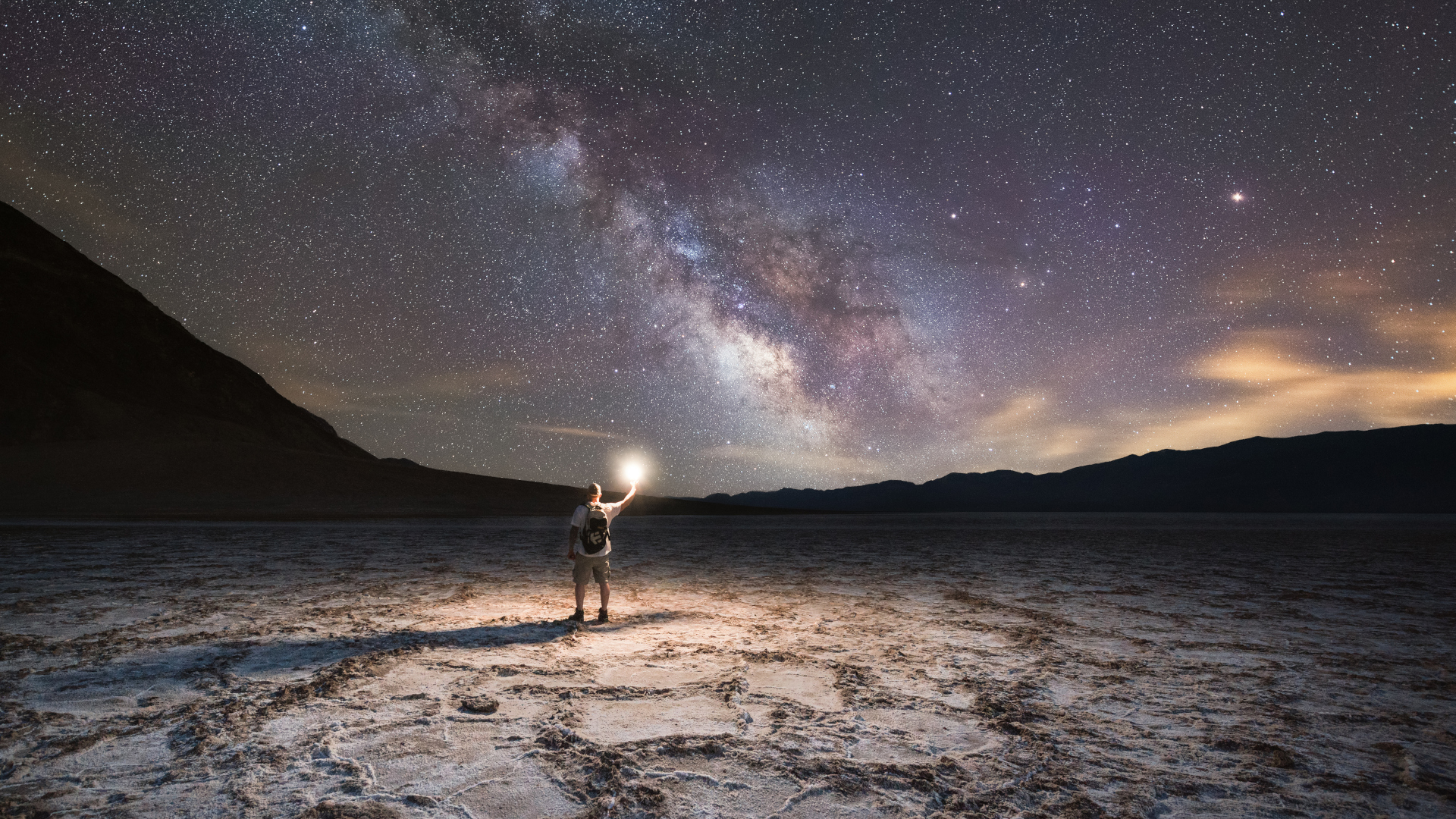 Un explorador viendo el cielo nocturno en Badwater Basin, Death Valley