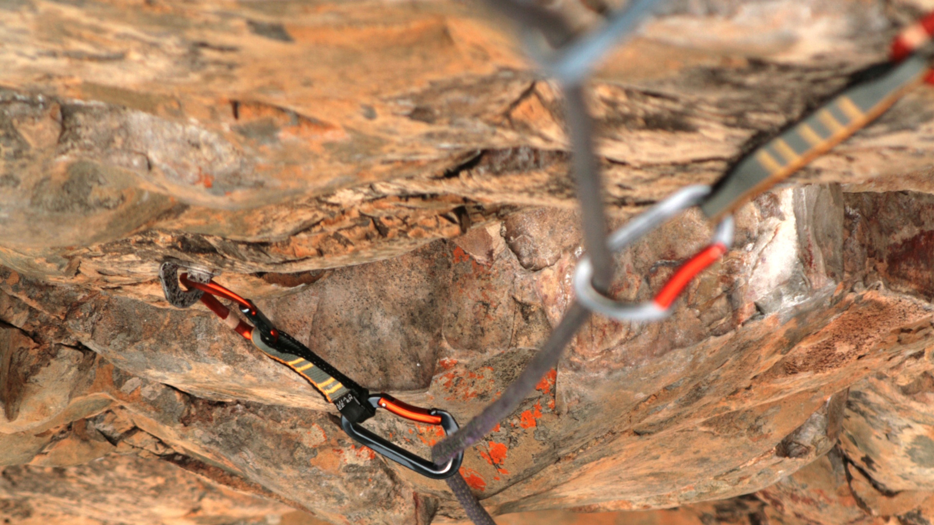 Una cuerda de escalada asegurada en pernos en la roca con cintas exprés