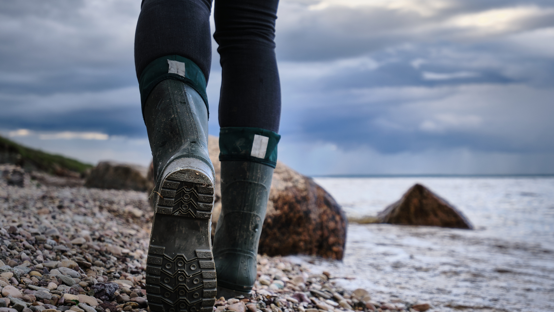 Cerca de un andador en una playa de guijarros usando botas de agua