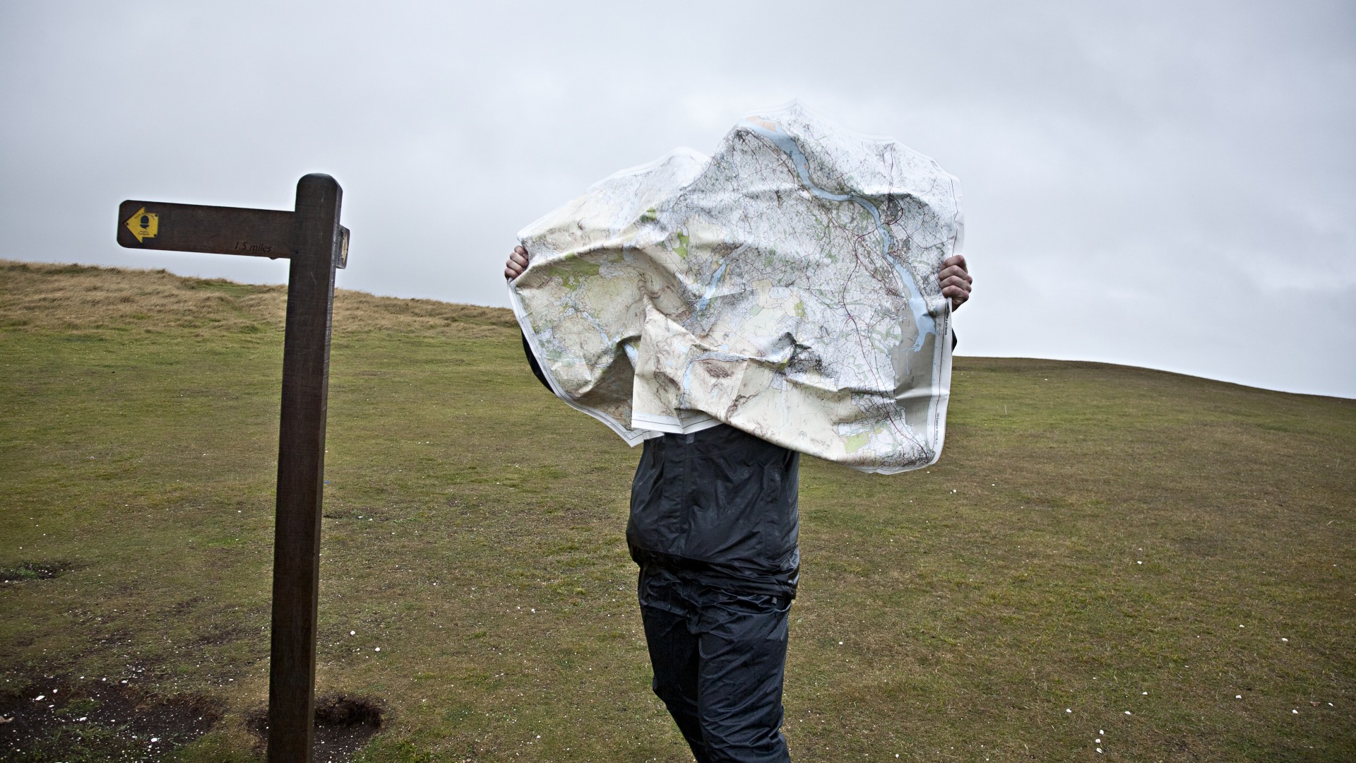Un excursionista lucha con su mapa en el viento