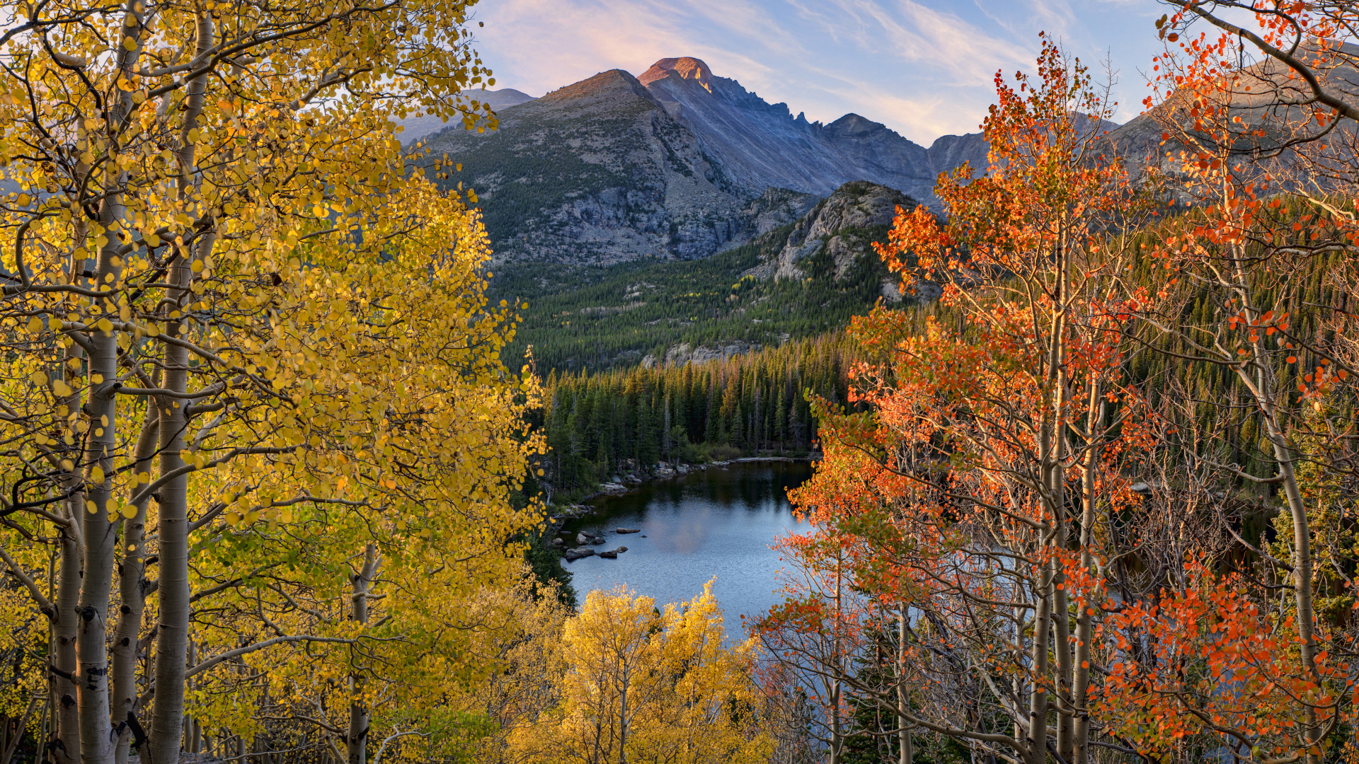 Un lago en el Parque Nacional de las Montañas Rocosas enmarcado por álamos dorados en otoño