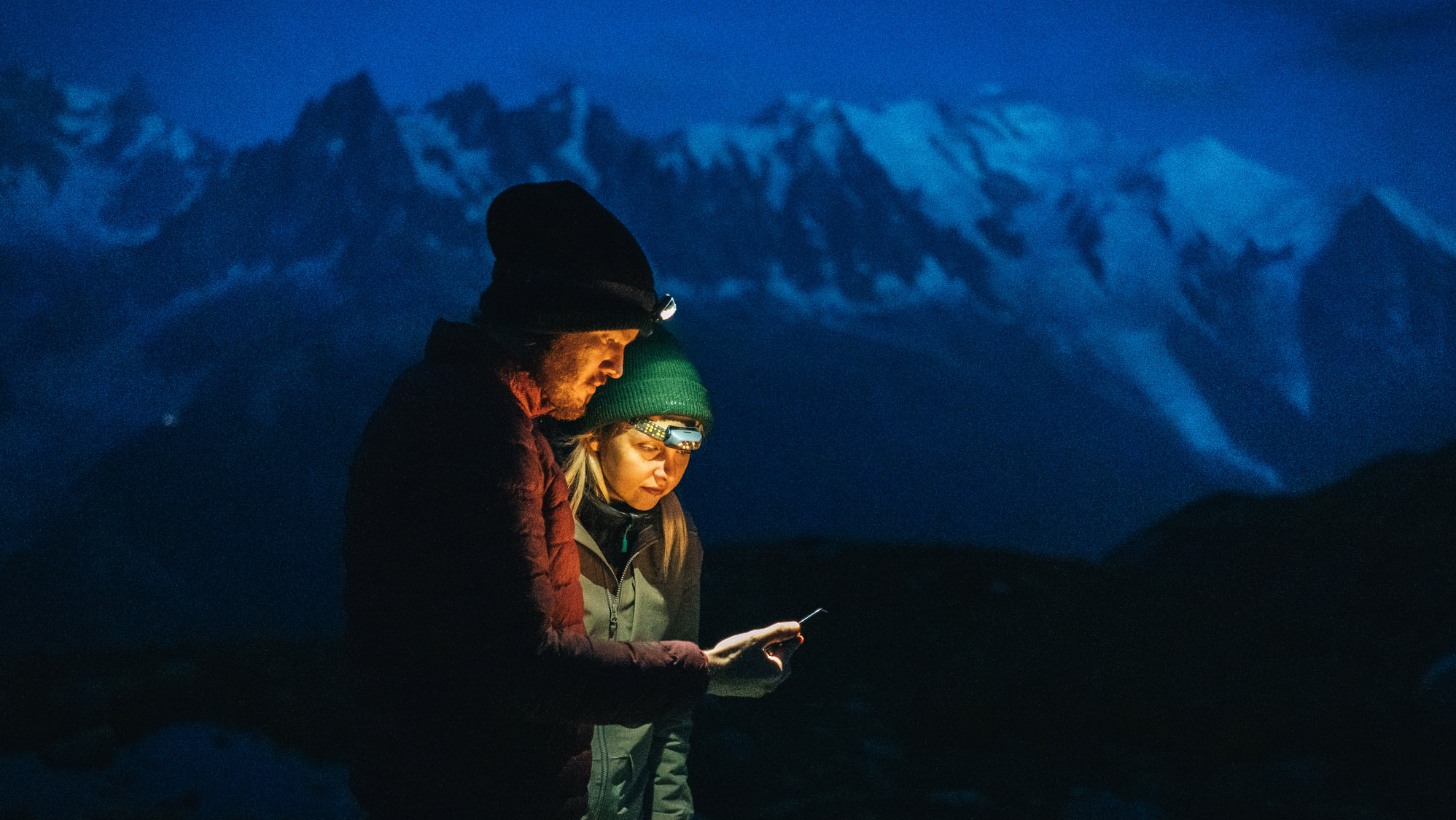 qué hacer si te pierdes haciendo senderismo: pareja de senderismo por la noche mirando el teléfono