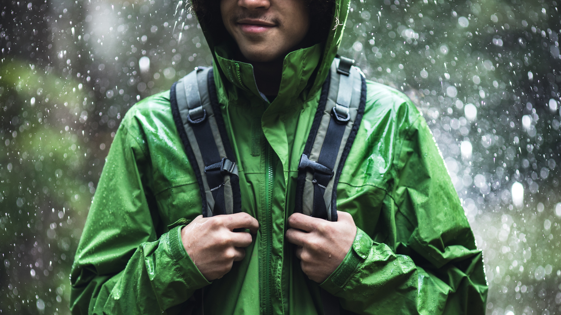 Un hombre haciendo senderismo bajo la lluvia con una chaqueta impermeable verde
