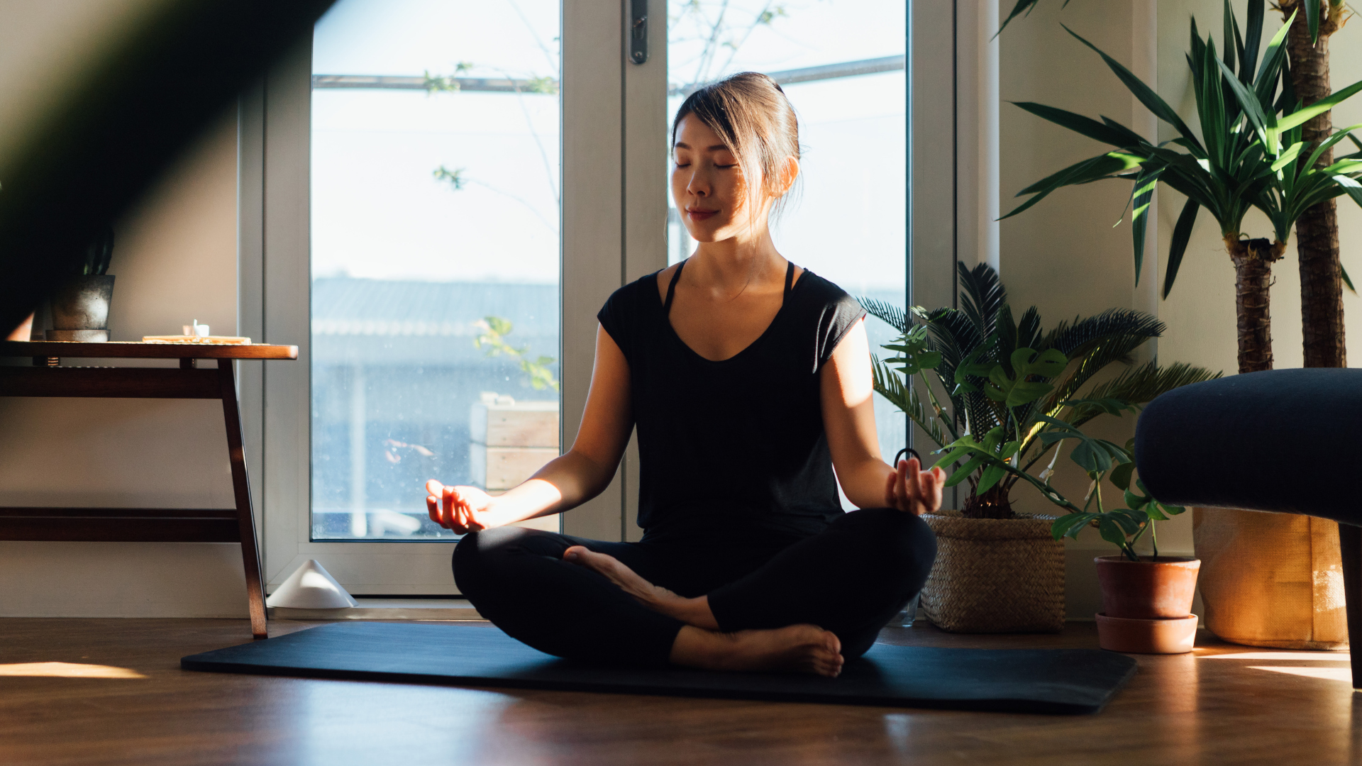 Una mujer meditando en su colchoneta de yoga en casa