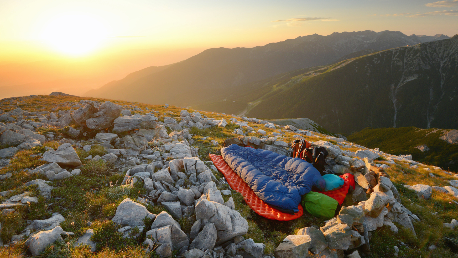 Camper en un saco bivy en una montaña al amanecer.
